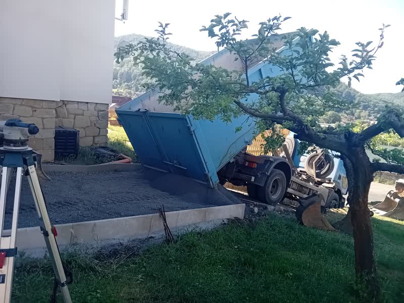Sklápěč vyklápí materiál na pozemku